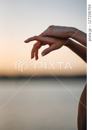 Female hands against the background of the river and sunset. 127206704