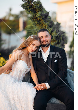 Gentle and happy bride and groom at sunset in the park on a bench. Gentle and happy bride and groom at sunset in the park on a bench. 127206712