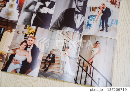 Printed wedding photos laid out on a wooden surface. 127206719