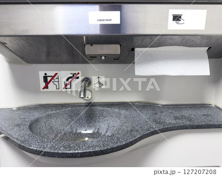 Modern compact sink with integrated paper towel dispenser, soap label and warning signs for hygiene and safety, designed for use in public transport or compact sanitary environments Modern compact sink with integrated paper towel dispenser, soap label and warning signs for hygiene and safety, designed for use in public transport or compact sanitary environments 127207208
