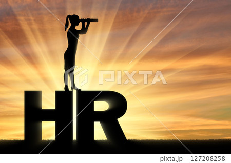 Silhouette of a woman standing on the letters HR and looking through binoculars. Hiring concept Silhouette of a woman standing on the letters HR and looking through binoculars. Hiring concept 127208258