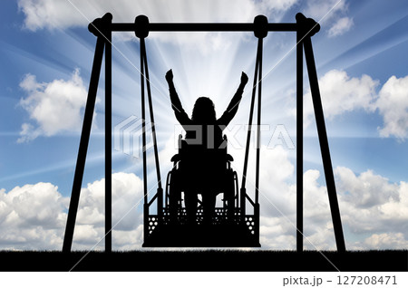 Silhouette of a happy woman is a disabled person in a wheelchair on an adaptive swing for disabled people 127208471