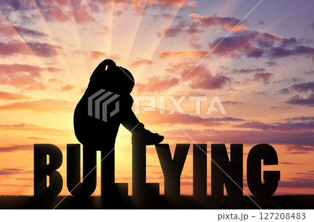 Silhouette of a sad girl sitting on the word bullying 127208483