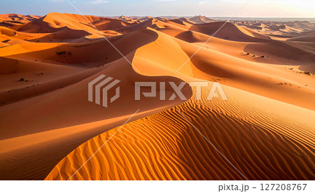 Sahara desert, showcasing pristine sand patterns and intricate wind carved ripple textures, The warm golden hues of the endless sand dunes stretch under a clear sky, golden desert view Sahara desert, showcasing pristine sand patterns and intricate wind carved ripple textures, The warm golden hues of the endless sand dunes stretch under a clear sky, golden desert view 127208767