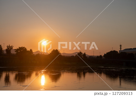 美しい夕日を映す公園の池の水面 127209313