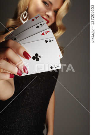 Four aces playing cards in woman's hand. Player with poker quads combination. Elegant female hands with red manicure 127209552