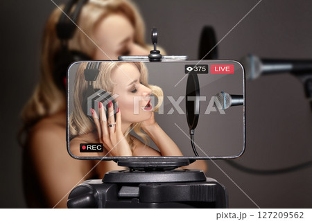 Confident female artist broadcasting from a home studio, creating digital content for her audience. Concept of modern music production, self-promotion, and live performance Confident female artist broadcasting from a home studio, creating digital content for her audience. Concept of modern music production, self-promotion, and live performance 127209562