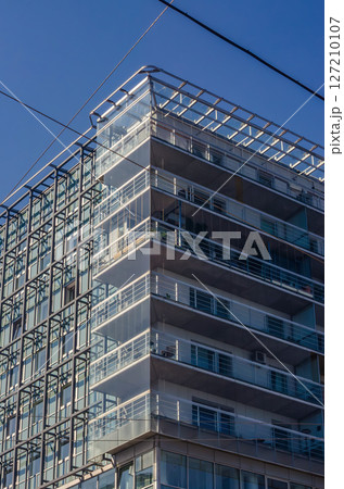Modern office building with glass facade and balconies under clear blue sky. High quality photo 127210107