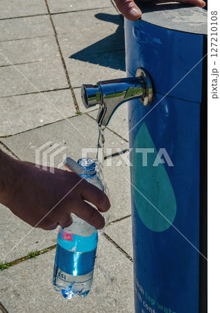Filling reusable bottle with fresh drinking water from a public tap. High quality photo 127210108