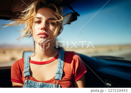 A woman in a red shirt and blue overalls is sitting in a car A woman in a red shirt and blue overalls is sitting in a car 127210455
