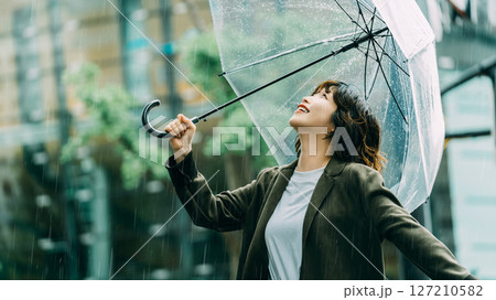 雨の中で楽しそうに傘をさす笑顔の女性(梅雨・6月) 雨の中で楽しそうに傘をさす笑顔の女性(梅雨・6月) 127210582