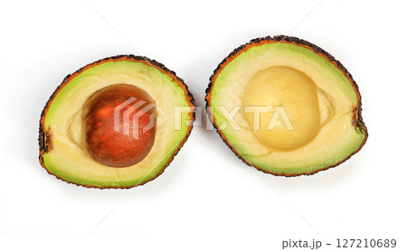 Ripe avocado (hass or bilse variety) cut to halves, with yellow green pulp showing, seed in one half, view from above isolated on white background Ripe avocado (hass or bilse variety) cut to halves, with yellow green pulp showing, seed in one half, view from above isolated on white background 127210689