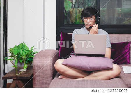 Businessman meeting online via video call on laptop in home office. Man wear headphone video calling or distance education e-leaning online course. 127210692