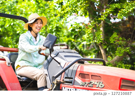 トラクターで畑を耕す女性 127210887