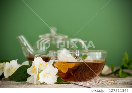 Green tea with jasmine in a glass teapot on a green background Green tea with jasmine in a glass teapot on a green background 127211345