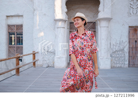 Young woman in an ethnic dress and hat exploring Al Seef Park in Dubai. Surrounded by traditional Emirati architecture and modern vibes, she enjoys the charm of Dubai Creek's cultural heritage. Young woman in an ethnic dress and hat exploring Al Seef Park in Dubai. Surrounded by traditional Emirati architecture and modern vibes, she enjoys the charm of Dubai Creek's cultural heritage. 127211996