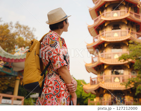 Woman Exploring Colorful Streets Near Buddhist Temples in Bangkok. Young traveler walking through the vibrant streets of Bangkok, admiring intricate temple details and lively surroundings.. Woman Exploring Colorful Streets Near Buddhist Temples in Bangkok. Young traveler walking through the vibrant streets of Bangkok, admiring intricate temple details and lively surroundings.. 127212000