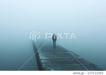A man stands alone on the edge of a pier, looking into the thick fog. Generated by artificial intelligence A man stands alone on the edge of a pier, looking into the thick fog. Generated by artificial intelligence 127212305