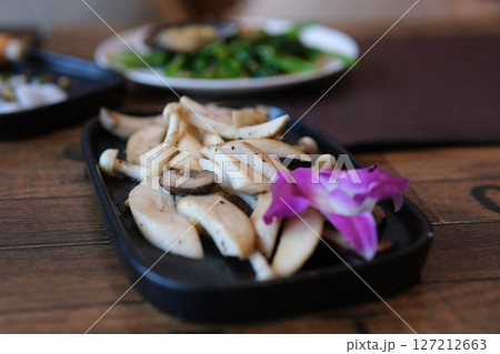 Home cook cuts oyster mushrooms into pieces Cozy kitchen with wooden table, kitchenware, vegetables, herbs and ingredients for cooking. Healthy vegan food, culinary, recipes, food blogging 127212663