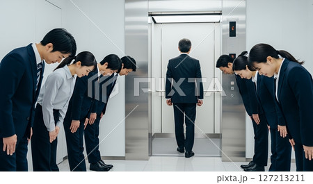 エレベーターに乗り込む男性と、整列してお辞儀をする会社員たち 127213211