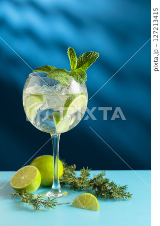 Cocktails gin and tonic with ice and lime slices on a blue background. 127213415
