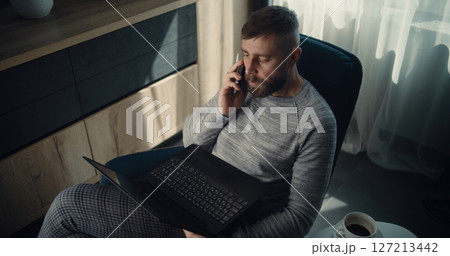 High Angle of Businessman Having Phone Call, Working on Laptop, Monitoring Real-Time Stocks 127213442