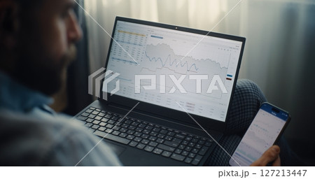 Close Up of Financial Expert Working on Smartphone and Laptop in Online Trading App 127213447