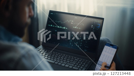 Close Up of Stock Trader Monitoring Real-Time Stocks in Trading App Using Smartphone and Laptop Close Up of Stock Trader Monitoring Real-Time Stocks in Trading App Using Smartphone and Laptop 127213448