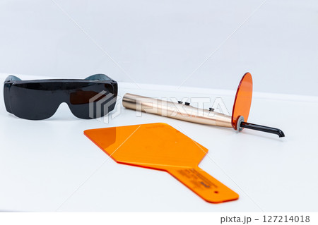 A Close-Up View of Dental Tools Including Protective Eyewear, Light Guide, and a Composite Cure Light for Safe Dental Procedures in Modern Practices 127214018