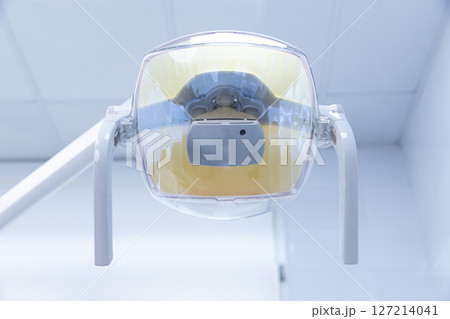 Close-Up View of a Dental Light Fixture in a Modern Clinic: Essential Equipment for Dental Procedures and Patient Comfort During Treatment Sessions Close-Up View of a Dental Light Fixture in a Modern Clinic: Essential Equipment for Dental Procedures and Patient Comfort During Treatment Sessions 127214041