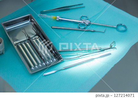 A Collection of Dental Instruments on a Light Blue Surface in a Clean Medical Environment Ready for Clinical Procedures and Patient Care with High-Quality Surgical Tools Visible 127214071