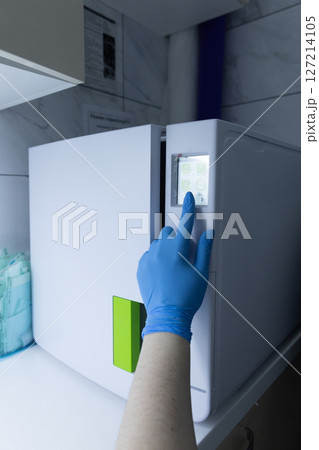 A Close-up View of a Hand in a Blue Glove Interacting with a Modern Medical Refrigerator Displaying Digital Controls in a Professional Environment A Close-up View of a Hand in a Blue Glove Interacting with a Modern Medical Refrigerator Displaying Digital Controls in a Professional Environment 127214105