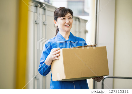 物流倉庫で段ボールを運ぶ50代の女性 物流倉庫で段ボールを運ぶ50代の女性 127215331