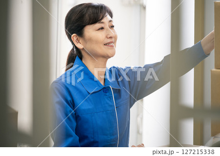作業服を着て物流倉庫で働くミドル世代の女性 127215338