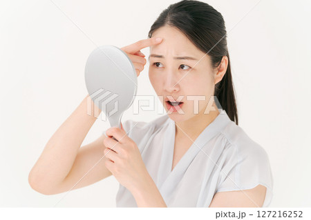 鏡を見て困った表情の女性 127216252
