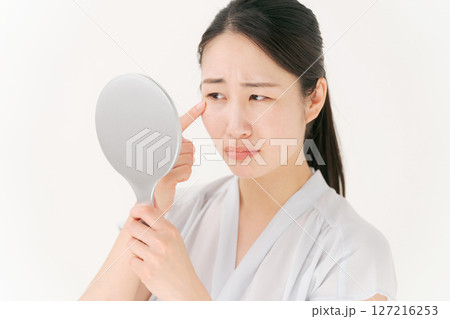 鏡を見て困った表情の女性 127216253
