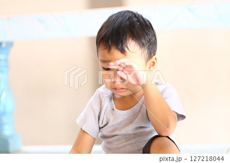 Young Child with Tearful Expression Sitting on Floor, Capturing Around Emotional Moment of Sadness and Reflection in Warm Natural Light Setting Young Child with Tearful Expression Sitting on Floor, Capturing Around Emotional Moment of Sadness and Reflection in Warm Natural Light Setting 127218044