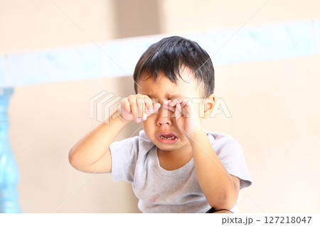 Emotionally distressed young boy with tears in his eyes, expressing sadness and vulnerability while sitting indoors in a simple, soft-lit environment. Emotionally distressed young boy with tears in his eyes, expressing sadness and vulnerability while sitting indoors in a simple, soft-lit environment. 127218047