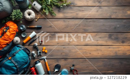 A travel backpack and hiking gear arranged on a wooden floor, perfect for a vacation in the forest or camping trip 127218229