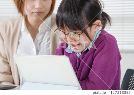 タブレットを使って眼鏡をかけた女の子は楽しそうに勉強する タブレットを使って眼鏡をかけた女の子は楽しそうに勉強する 127218882