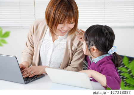 一緒にタブレット学習する小学生と在宅勤務のママ 一緒にタブレット学習する小学生と在宅勤務のママ 127218887
