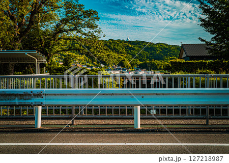ガードレール越しに望む郊外の山と町の風景 127218987