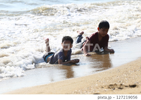 Two Young Boys Enjoying a Warm Day at the Beach, Rolling on the Sand and Playing in the Gentle Waves of the Ocean, Capturing Childhood Joy and Freedom Two Young Boys Enjoying a Warm Day at the Beach, Rolling on the Sand and Playing in the Gentle Waves of the Ocean, Capturing Childhood Joy and Freedom 127219056