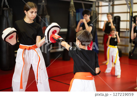 Teenage girl in boxing mitts trains with boy in boxing gloves Teenage girl in boxing mitts trains with boy in boxing gloves 127219059