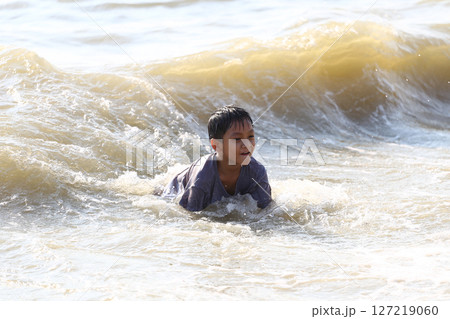 Joyful Child Playing in Ocean Waves at the Beach, Capturing the Essence of Youthful Adventure and Fun in a Beautiful Seaside Setting Joyful Child Playing in Ocean Waves at the Beach, Capturing the Essence of Youthful Adventure and Fun in a Beautiful Seaside Setting 127219060