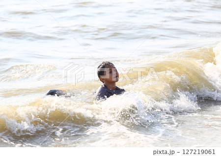 A Young Boy Enjoying a Swim in the Ocean Waves, Capturing the Joy and Freedom of Childhood on a Sunny Day at the Beach with Soft Sand and Gentle Surf A Young Boy Enjoying a Swim in the Ocean Waves, Capturing the Joy and Freedom of Childhood on a Sunny Day at the Beach with Soft Sand and Gentle Surf 127219061