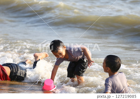 Children Playing in Shallow Ocean Water with Colorful Toys, Enjoying Sunny Day at the Beach, Capturing Joyful Moments of Summer Fun and Laughter by the Shoreline Children Playing in Shallow Ocean Water with Colorful Toys, Enjoying Sunny Day at the Beach, Capturing Joyful Moments of Summer Fun and Laughter by the Shoreline 127219085