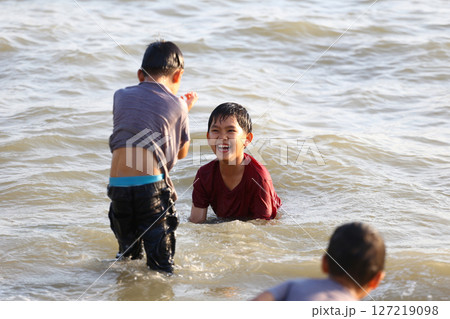 Joyful Children Playing Together in Shallow Water, Splashing and Laughing Under Bright Sunlight, Cherishing Moments of Fun and Friendship by the Beach 127219098