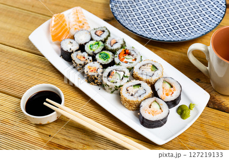 Set of different types of sushi served with sauce soy on board in cafe Set of different types of sushi served with sauce soy on board in cafe 127219133