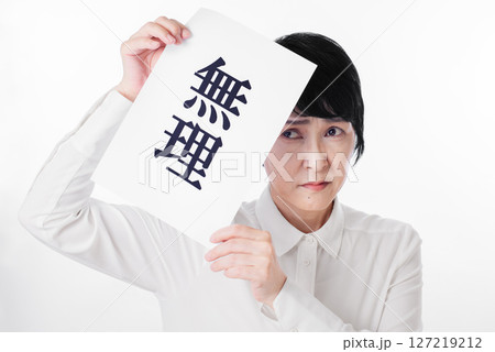 無理と書かれた紙を持ち怯えた表情の中年女性 無理と書かれた紙を持ち怯えた表情の中年女性 127219212